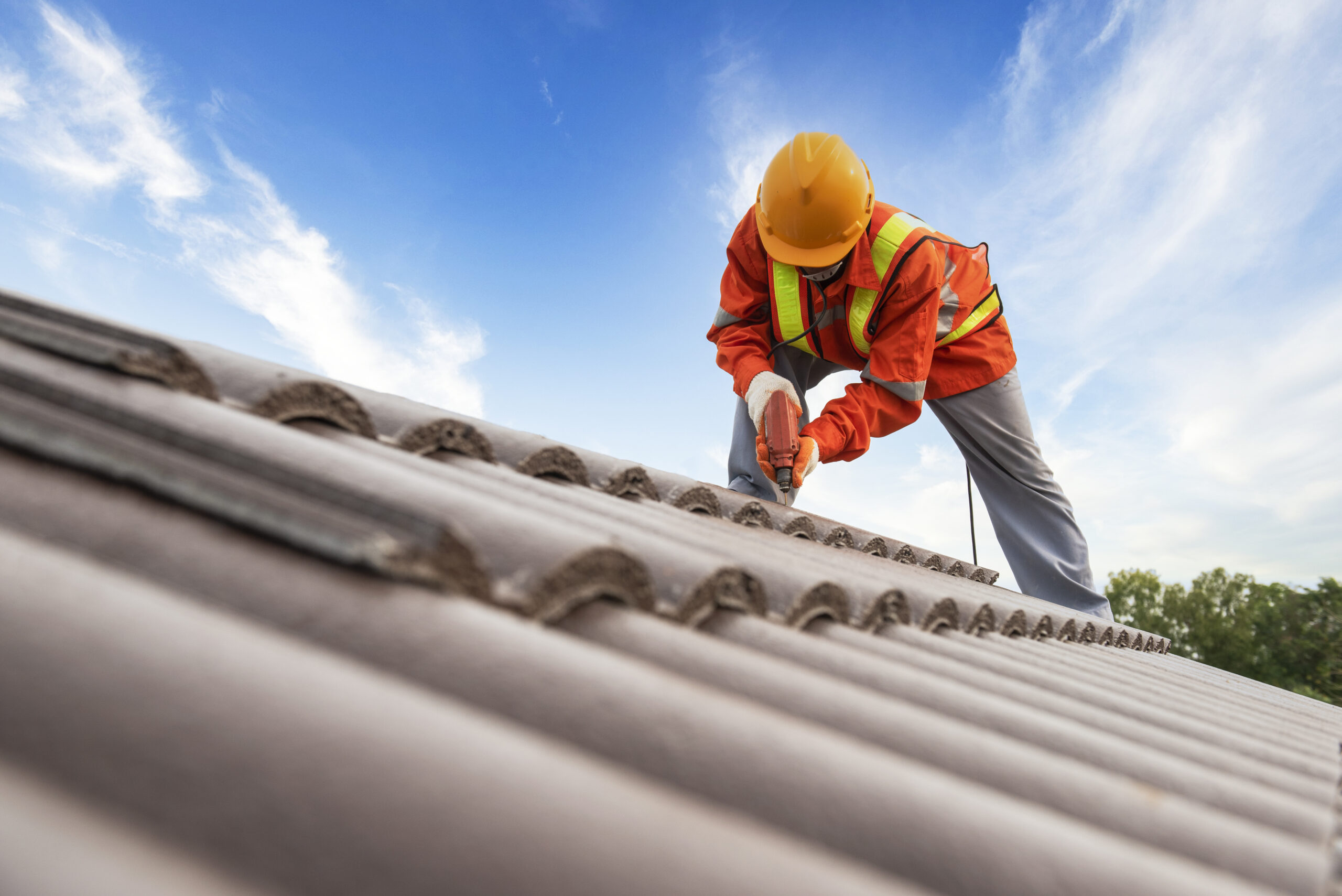 Builders in work clothes install new roofing tools, roofing tools, electric drill and use them on new wooden roofs with metal sheet Builders in work clothes install new roofing tools, roofing tools, electric drill and use them on new wooden roofs with metal sheet